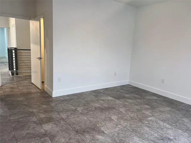 Large-format stone-style tile flooring, crisp neutral wall finish, and staircase featuring a metal horizontal-bar railing