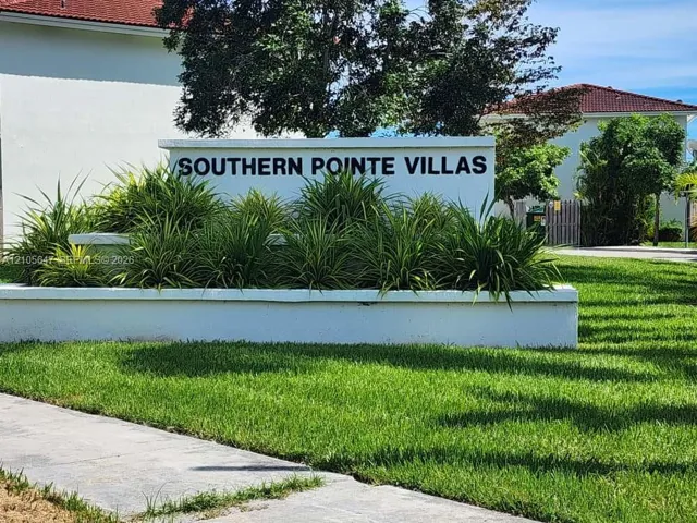 Stucco monument signage featuring tiered concrete planters, ornamental grasses, and landscaped grounds