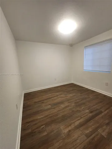 Interior room featuring wood-finish flooring, white walls, and a recessed ceiling light