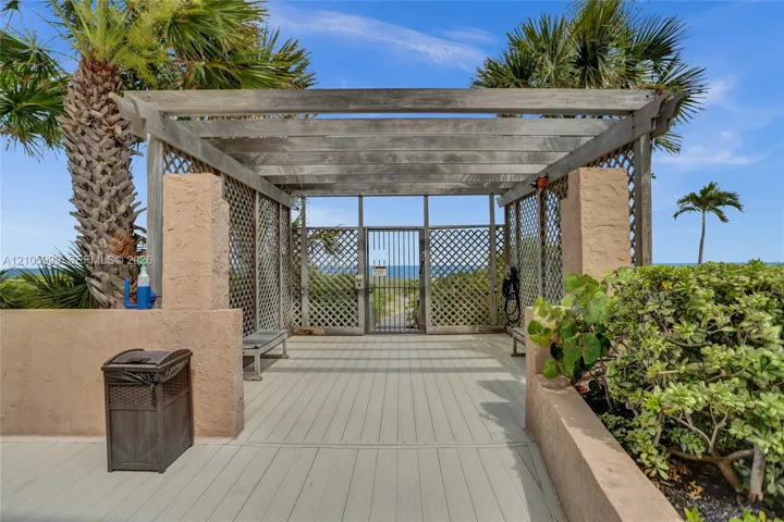 Wood-frame pergola with lattice side panels, solid surface decking, integrated benches, and gated access