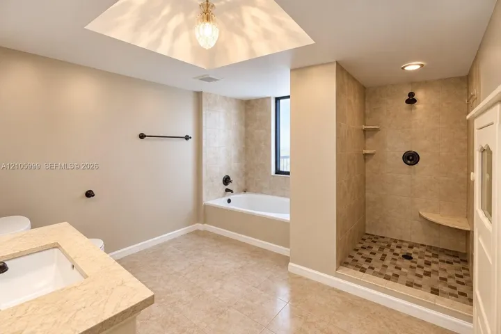 Bathroom featuring a walk-in shower with mosaic tile flooring, built-in corner bench, soaking tub, stone-surfaced vanity, and recessed ceiling lighting