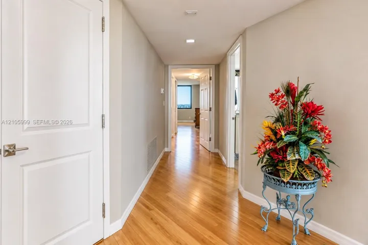 Hallway featuring wood-finish flooring, recessed lighting, and white paneled doors with satin nickel hardware