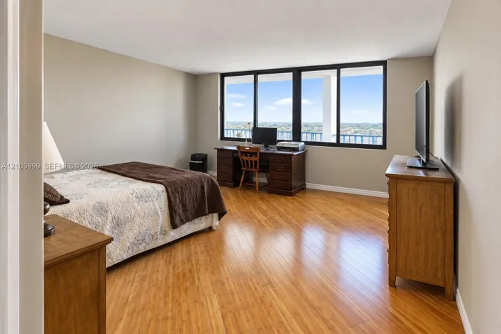 Wood-finish flooring, neutral wall tones, and expansive windows featuring black frames and outdoor scenery