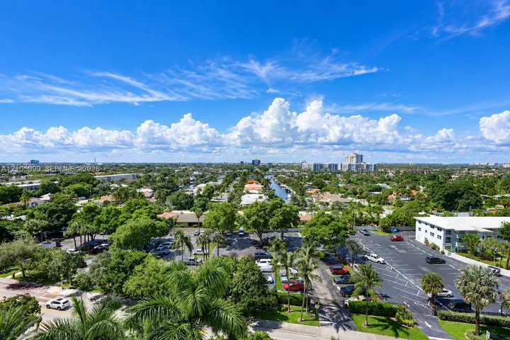 Aerial perspective featuring paved parking areas, mature palm trees, established landscaping, and a central waterway