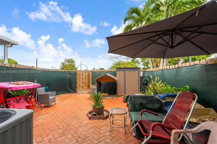 Enclosed outdoor area featuring herringbone-pattern brick paving, a wooden privacy fence, and a gated entrance