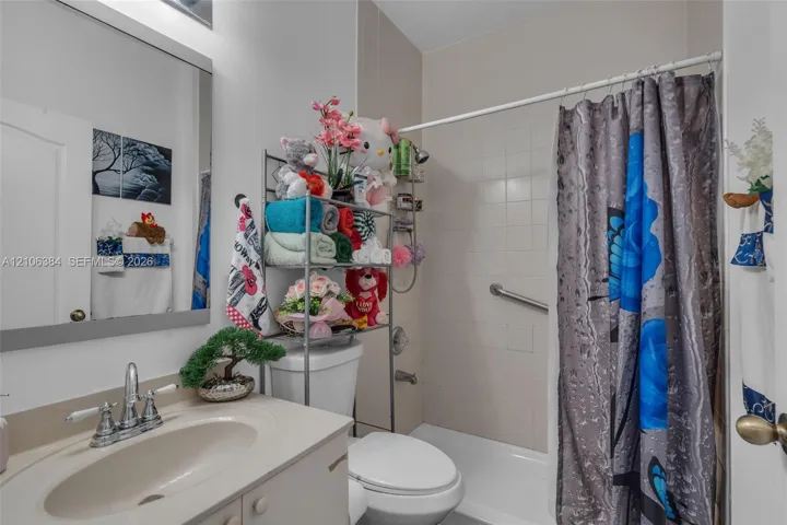 Bathroom featuring a vanity with an integrated basin, chrome dual-handle faucet, framed wall mirror, and a tub-shower combination with ceramic tile surround and installed safety grab bar