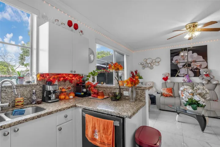 Kitchen featuring stone countertops, white cabinetry, a stainless steel undermount sink, and tile flooring