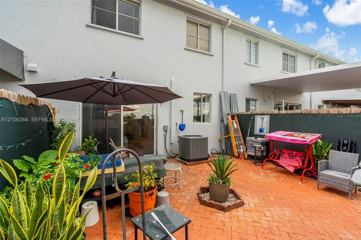 Patio area featuring herringbone-patterned brick pavers, sliding glass entry door, and an attached covered area