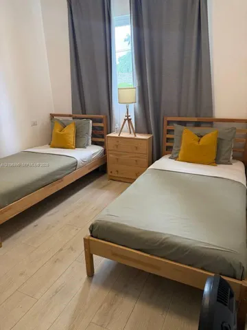 Wood-finish flooring and a central window with full-length drapery