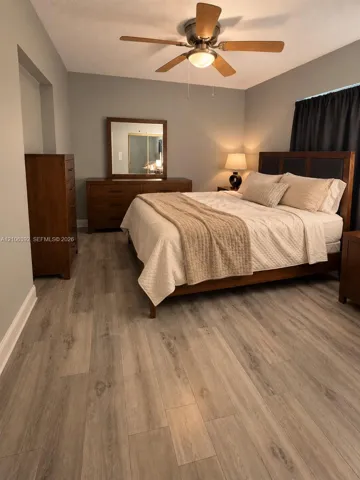 Neutral-toned interior walls featuring wood-finish flooring and a central ceiling fan with integrated lighting