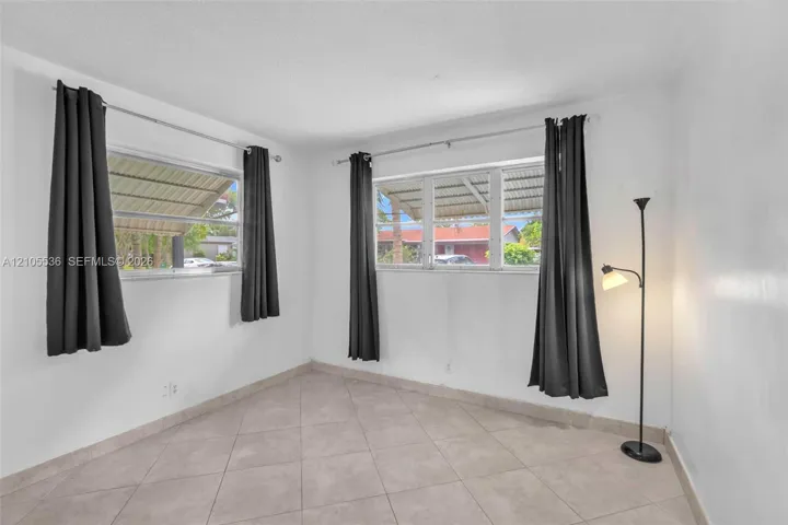Neutral-toned room featuring large windows, diamond-patterned tile flooring, and a textured ceiling finish