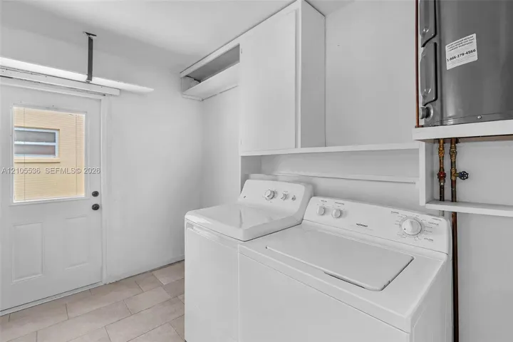Utility space featuring tile flooring, built-in overhead cabinetry, open shelving, and an exterior door with an inset window