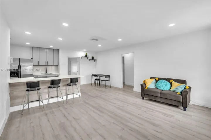 Kitchen featuring grey cabinetry, quartz countertops, a breakfast bar, recessed lighting, and wood-finish flooring