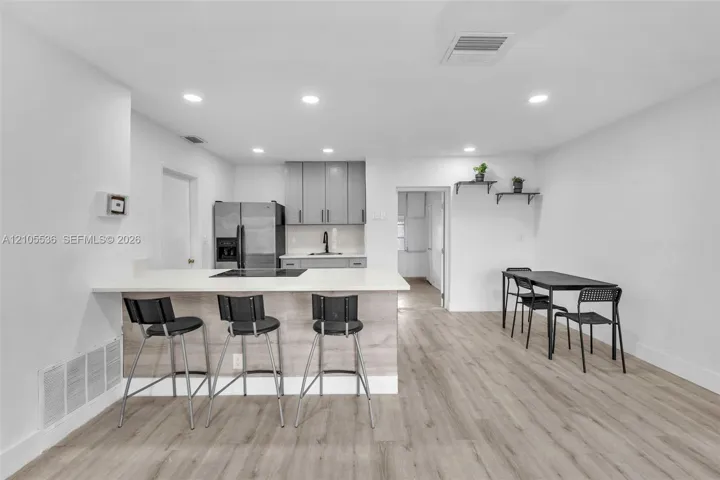 Kitchen featuring a wood-finish island with a stone countertop, grey cabinetry, stainless steel refrigerator, recessed lighting, and wood-finish flooring