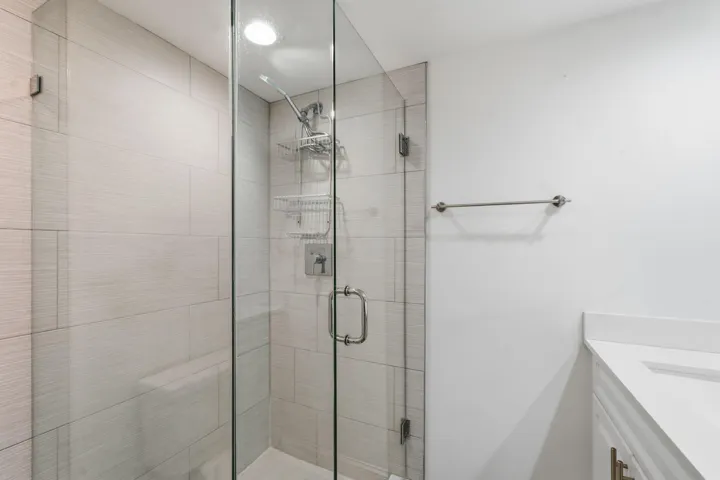 Glass-enclosed shower with subway tile surround, recessed lighting, and a chrome shower fixture
