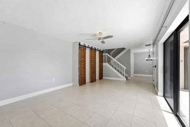Spacious interior featuring tile flooring, a contemporary ceiling fan, and wood-panel barn doors