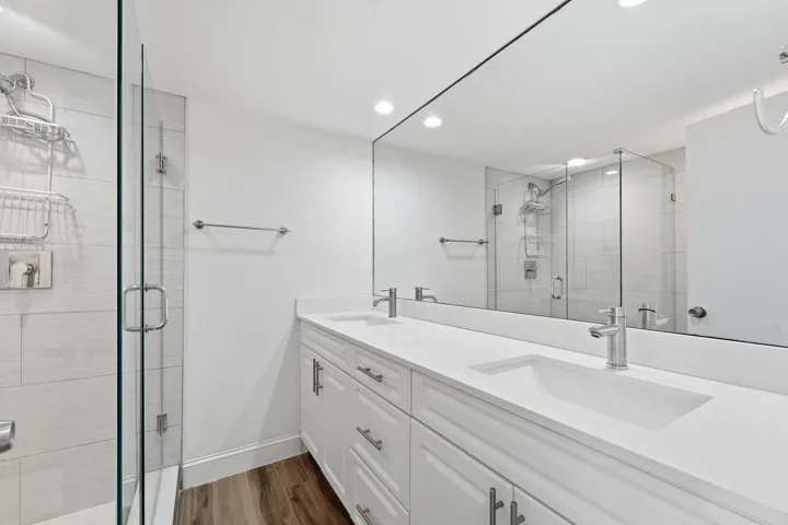 Dual vanity with integrated sinks, white cabinetry, and a full-width mirror