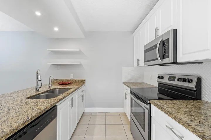 Kitchen featuring granite countertops, white cabinetry, stainless steel appliances, tile flooring, and recessed lighting