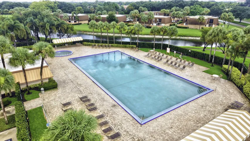 Expansive outdoor pool area featuring a rectangular swimming pool, a separate circular spa, and an extensive paver deck