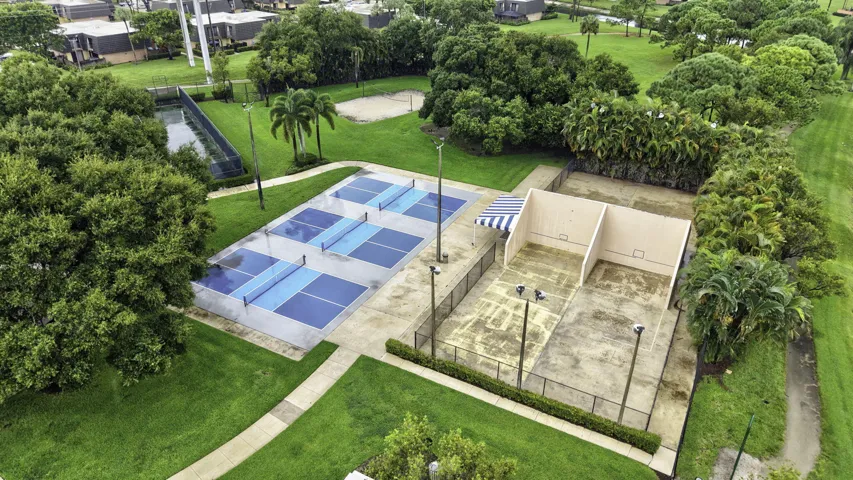 Multiple pickleball courts, two racquetball courts, a sand volleyball court, and lush landscaping