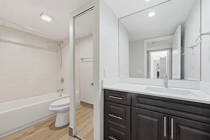 Bathroom with a dark wood-finish vanity, white countertop, integrated sink, and large wall-mounted mirror