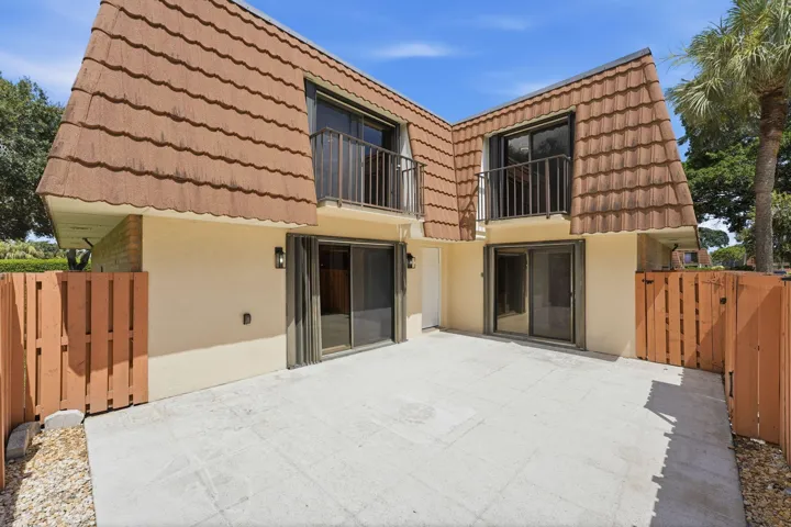 Private patio area with concrete pavers, dual sliding glass doors, and privacy fencing