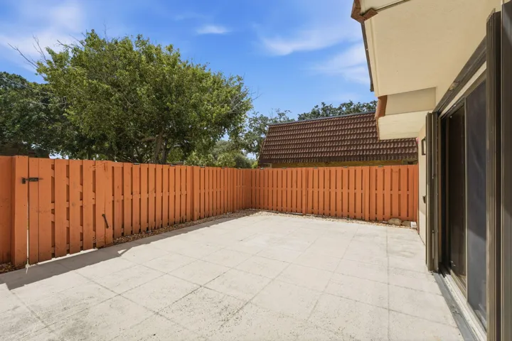 Paved outdoor patio space with wood fencing and a sliding glass door