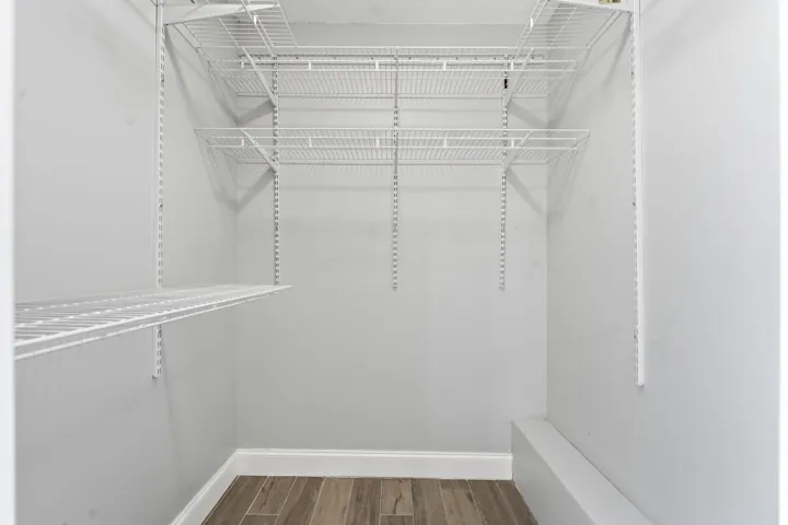 White wire shelving system, light gray wall paint, wood-finish flooring, and white trim