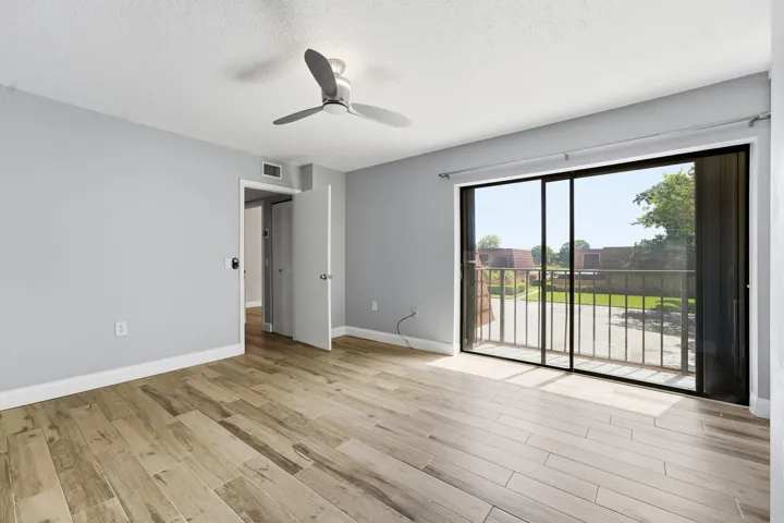 Wood-finish plank flooring, ceiling fan, and sliding glass door with balcony access