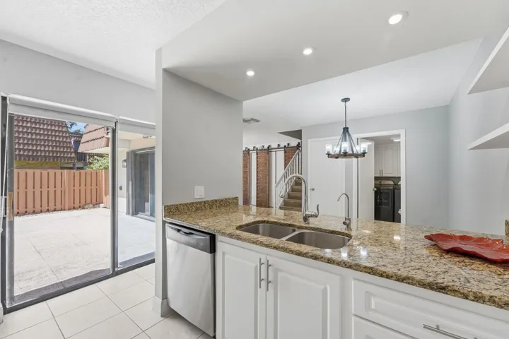 Kitchen featuring granite countertops, white cabinetry, stainless steel dishwasher, recessed lighting, and a dual basin sink