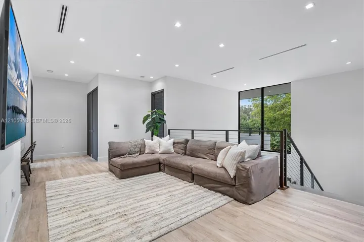 Open-concept space featuring light wood-finish flooring, recessed ceiling lighting, linear HVAC diffusers, and a staircase with a horizontal cable railing system