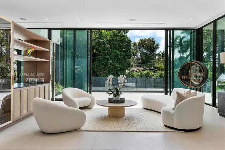 Floor-to-ceiling retractable glass walls, built-in recessed ceiling lighting, light-toned large-format tile flooring, and custom wood-paneled cabinetry with integrated shelving