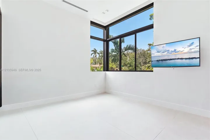 Corner windows with black frames, large-format tile flooring, and recessed ceiling lighting