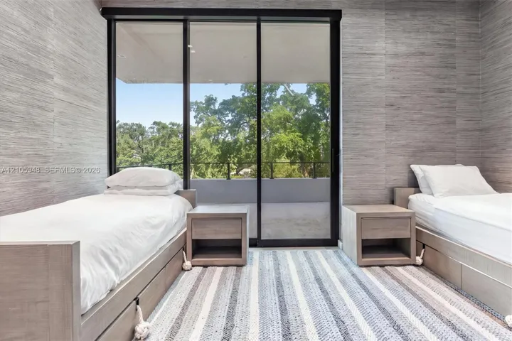 Textured wall coverings, floor-to-ceiling sliding glass doors, and a covered balcony featuring a black metal railing