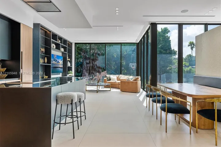 Open-concept interior featuring floor-to-ceiling glass walls, large-format tile flooring, recessed ceiling lighting, and custom built-in shelving