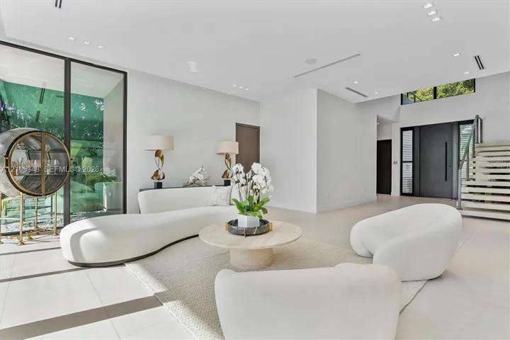 Open-concept living space featuring large-format tile flooring, floor-to-ceiling glass panel walls, recessed ceiling lighting, and a staircase with open risers
