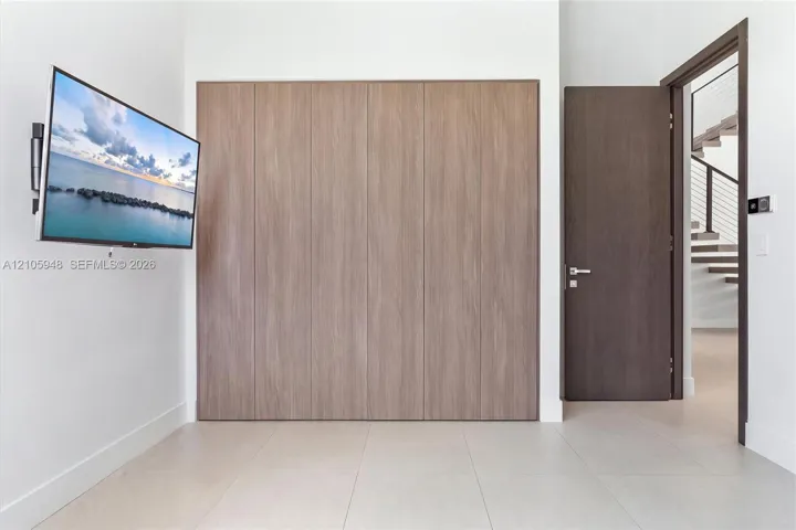Floor-to-ceiling wood-finish cabinetry, solid-core interior door with brushed metal hardware, and large-format tile flooring