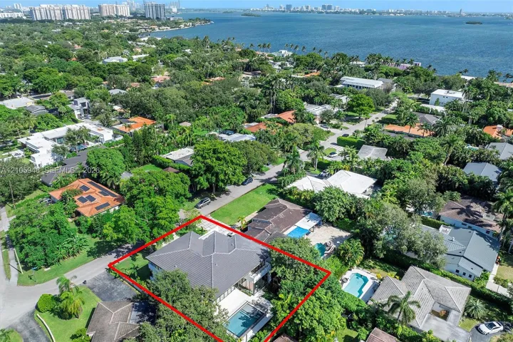 Aerial perspective featuring a residential property with a tiled roof, rectangular swimming pool, paved patio, and mature landscaping