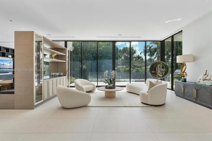 Open-concept living area featuring floor-to-ceiling glass walls, large-format tile flooring, recessed ceiling lighting, and a custom built-in wood-finish shelving unit