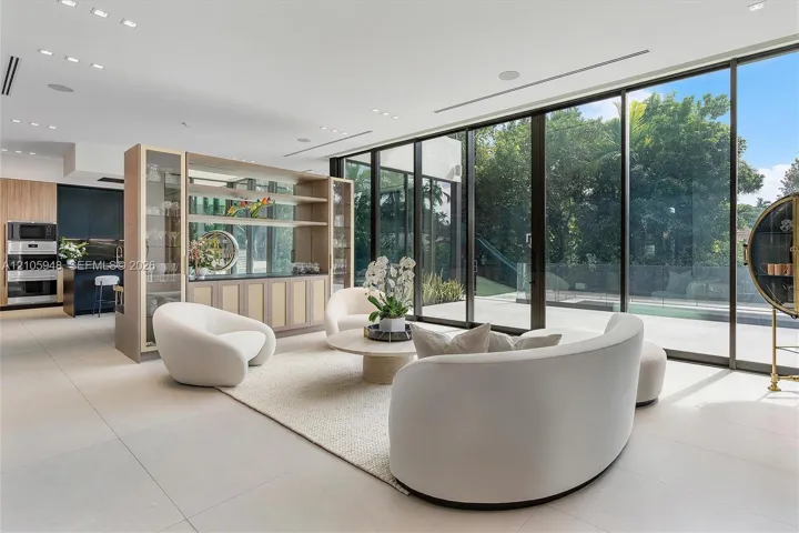 Floor-to-ceiling sliding glass doors, integrated custom shelving unit with glass-front cabinetry, large-format tile flooring, recessed lighting, and built-in wall oven and microwave