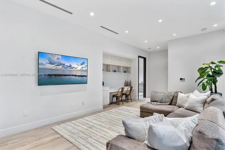 Room featuring wood-finish flooring, recessed lighting, linear HVAC diffusers, and built-in workstation with overhead cabinetry
