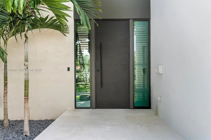 Entry featuring a dark horizontal-plank door with an elongated vertical handle, framed by full-height frosted glass sidelights on a neutral-toned stone landing