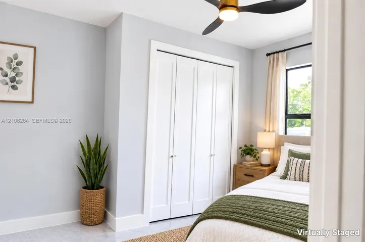 Neutral wall palette with white bi-fold closet doors, multi-pane window, and integrated matte black ceiling fan with light fixture