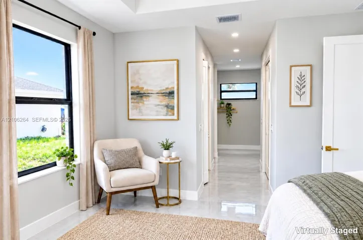 Neutral-toned interior space featuring light-colored stone-finish flooring, recessed lighting, and large windows with black frames