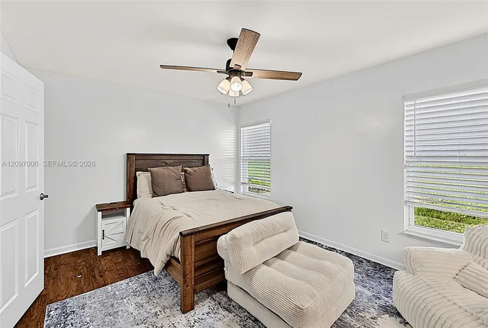 Wood-finish flooring, ceiling fan with integrated light fixture, and dual windows with horizontal blinds