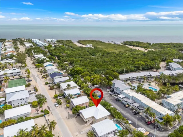 Aerial perspective of coastal residential property featuring a metal roof, elevated structure, and proximity to the coastline