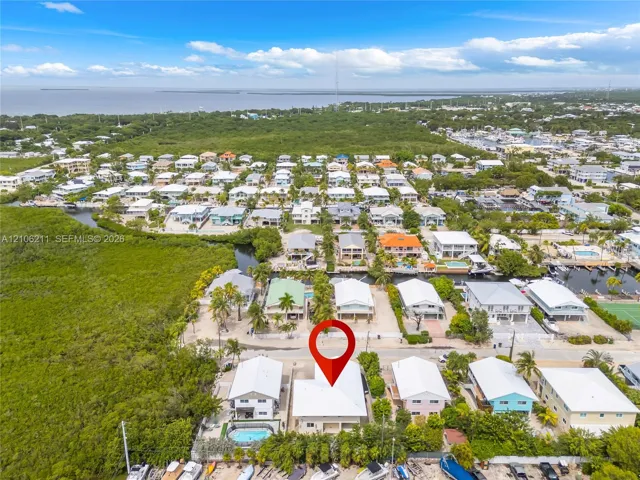 Aerial perspective of coastal residential property featuring an integrated swimming pool, waterfront access, and proximity to open water