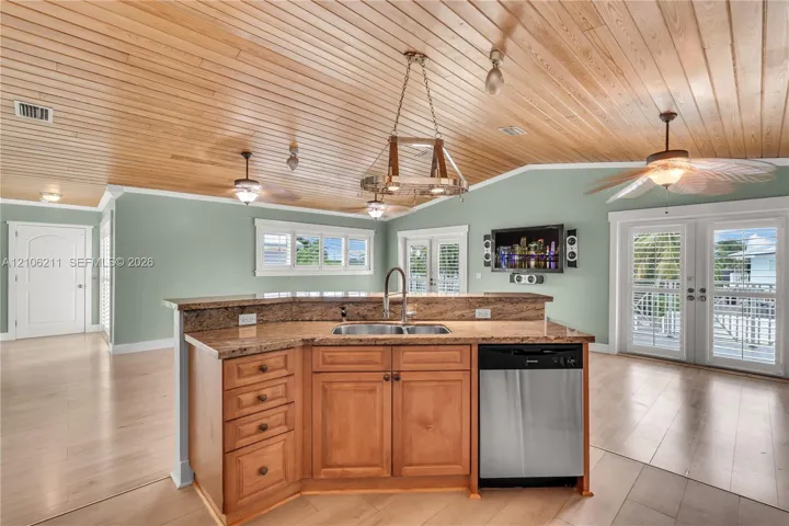 Kitchen featuring wood-paneled vaulted ceilings, natural wood cabinetry, stone countertops, a stainless steel dishwasher, and French doors