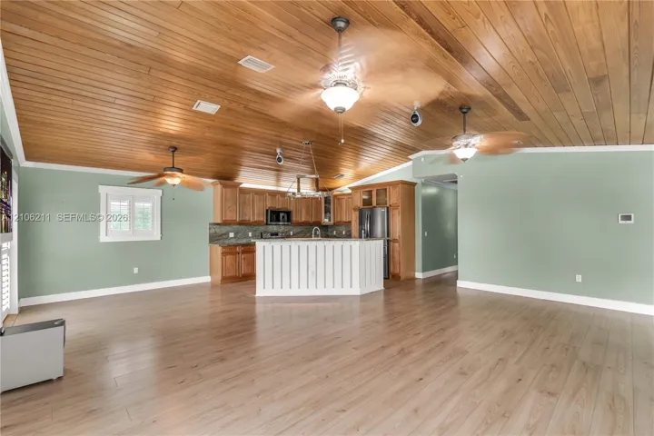 Vaulted tongue-and-groove wood plank ceiling, light wood-finish flooring, kitchen island with beadboard detailing, wood cabinetry, and recessed lighting
