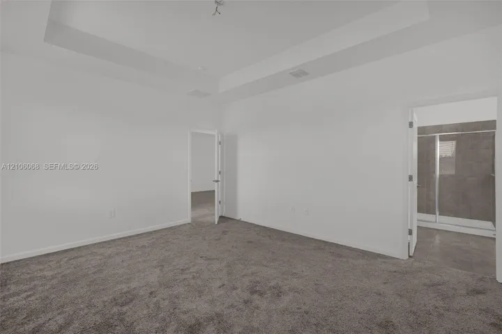 Room featuring a tray ceiling, wall-to-wall carpeting, and neutral wall color